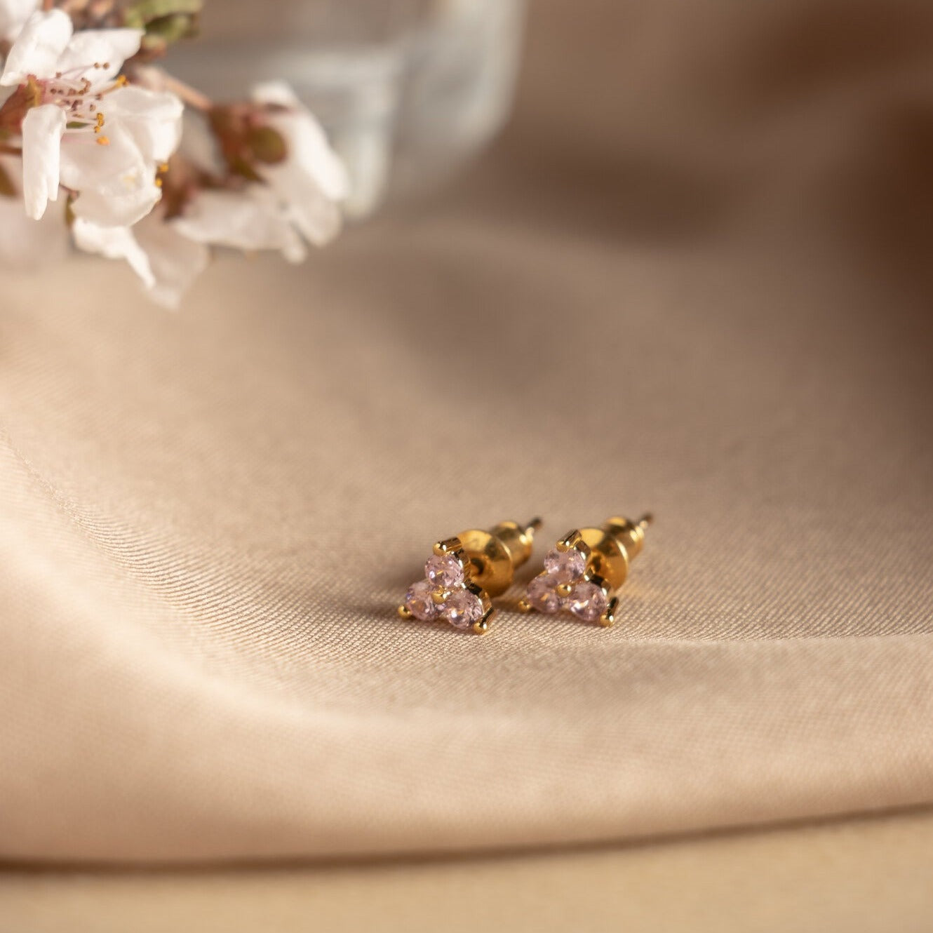 Piercing de forma floral con chapa de oro e incrustaciones de 3 piezas zirconia morada sobre tela.